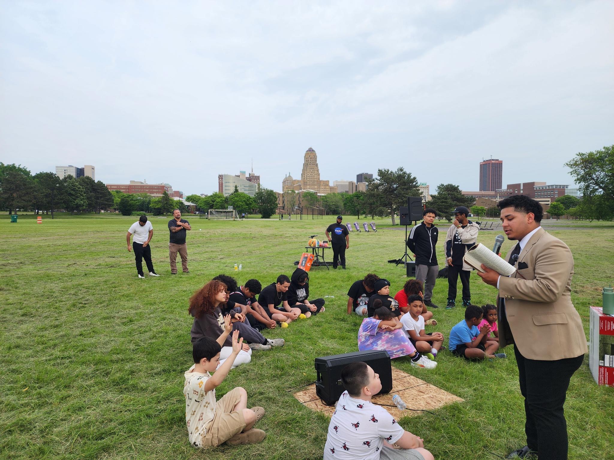 Outdoor gathering with heads bowed in prayer