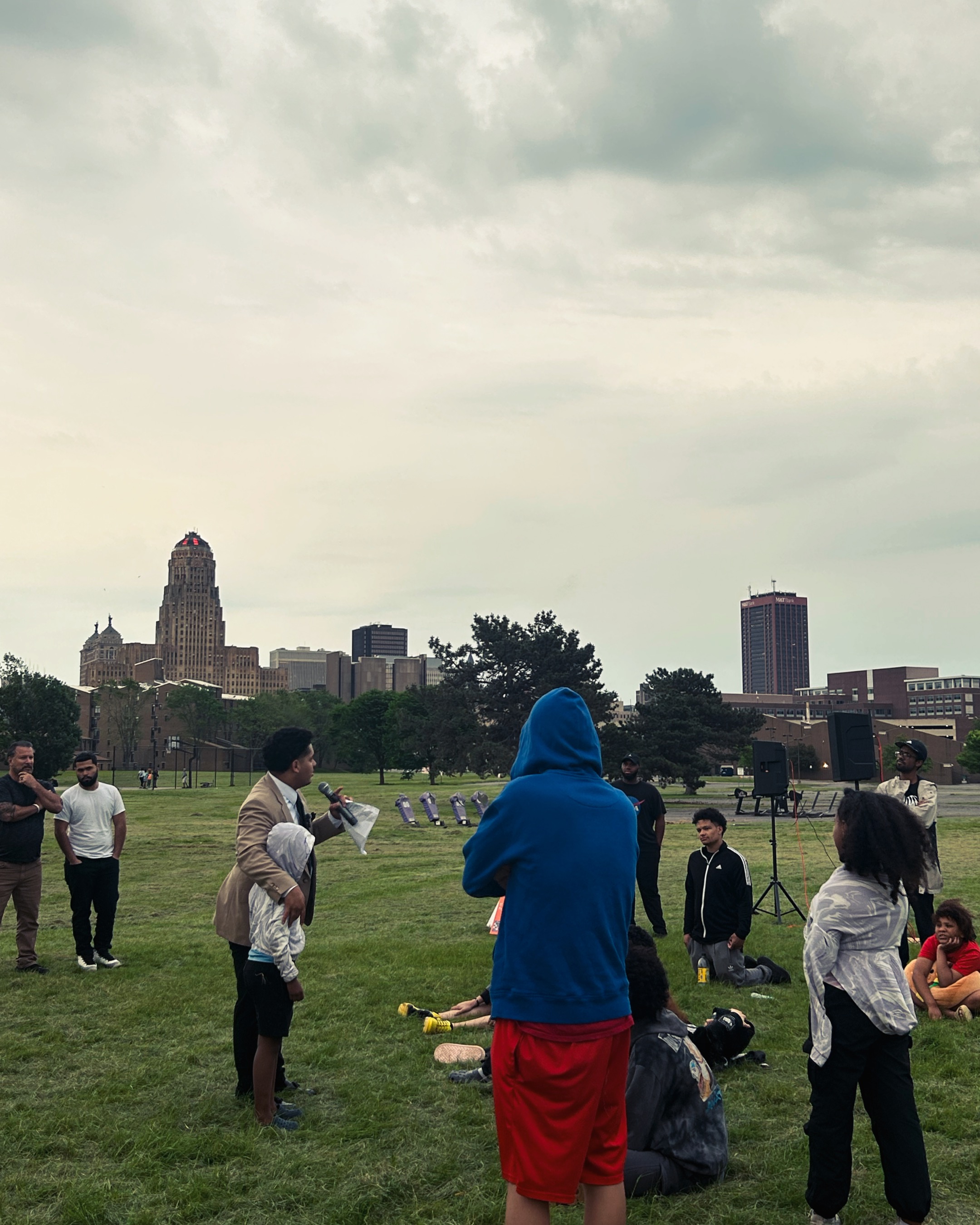 Outdoor evangelism in a Buffalo field with the city skyline in the distance