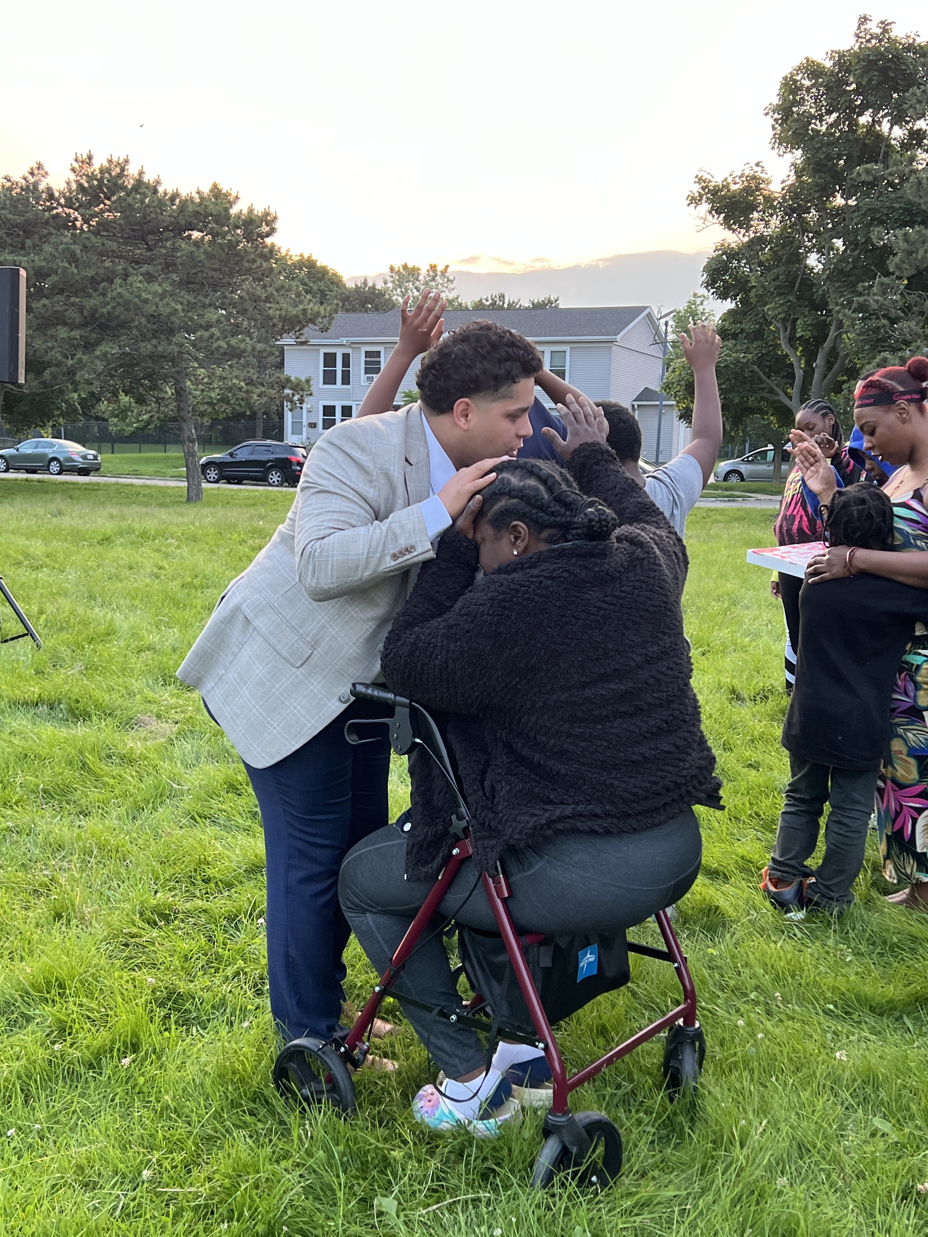 Sunset prayer over a woman in a walker, hands raised in worship around her