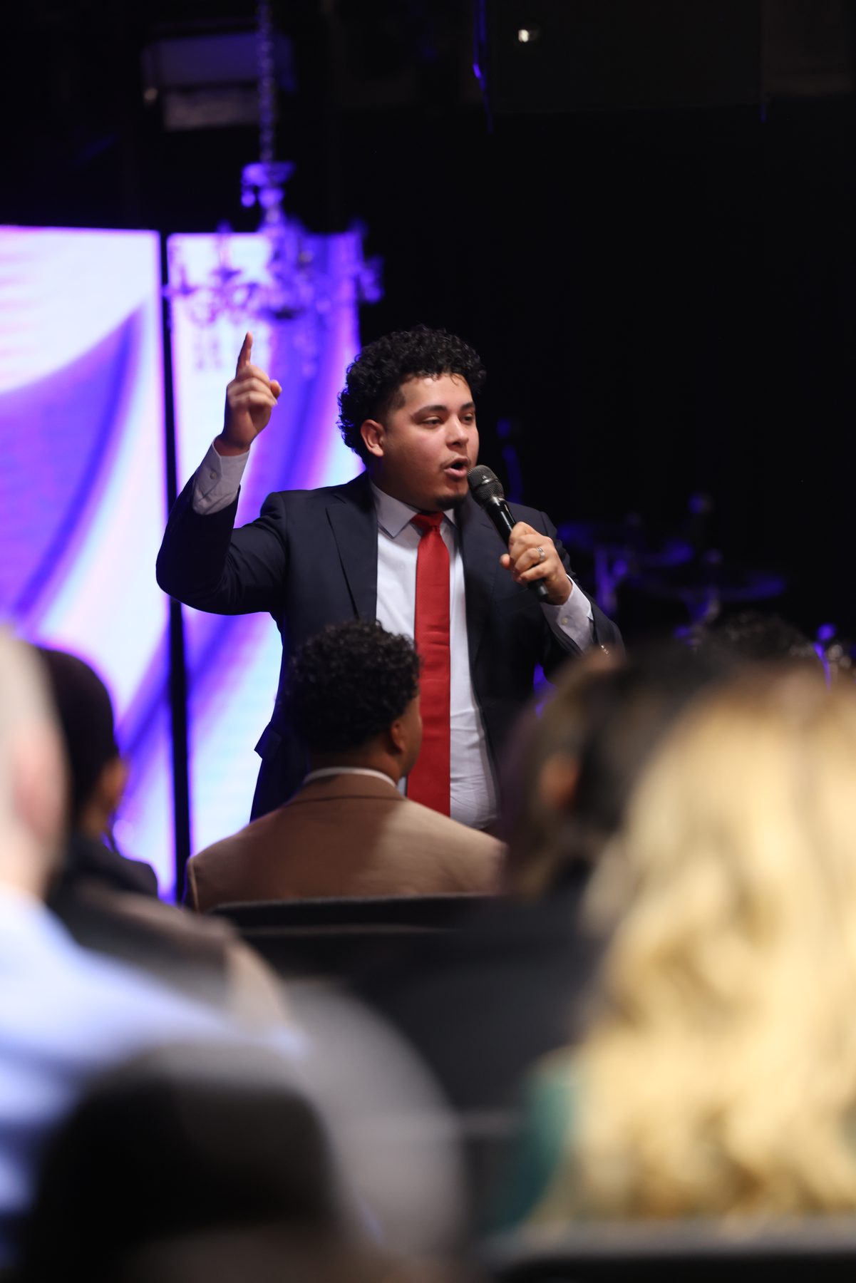 Evangelist Izaiah Diaz preaching at a recent crusade in suit and tie with microphone in hand