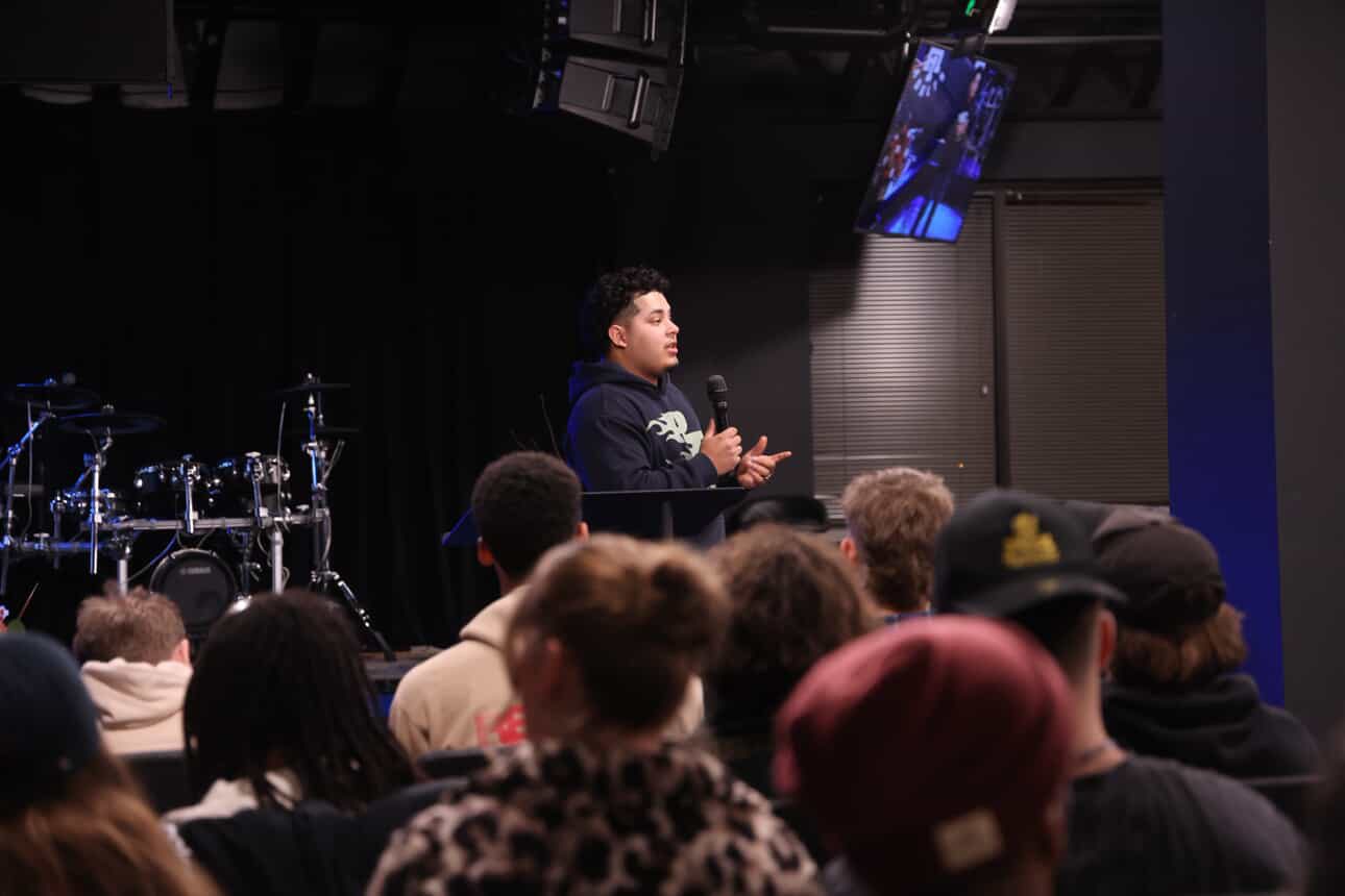 Izaiah preaching at a youth service from behind a music stand pulpit