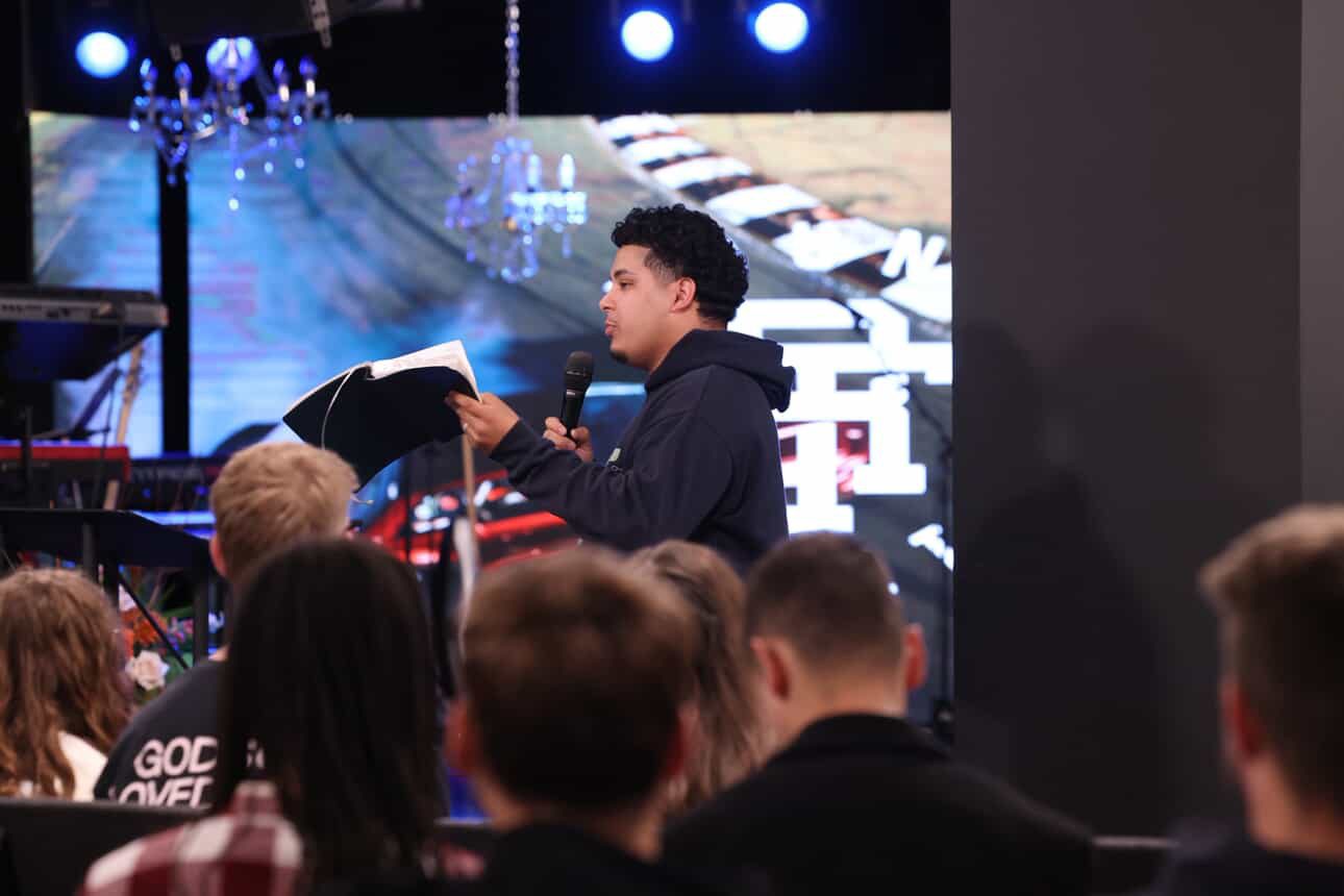 Izaiah preaching at a young adults service holding an open Bible